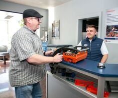 Two men are talking. One holds a radio control.